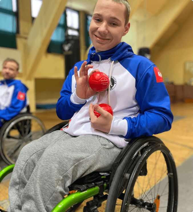 Chłopak z czerwoną piłką na wózku